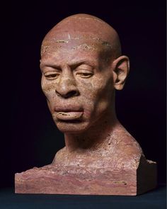 an old clay head with eyes closed on a black background