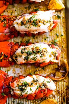 cooked lobsters on a baking sheet with lemon wedges and parsley garnish