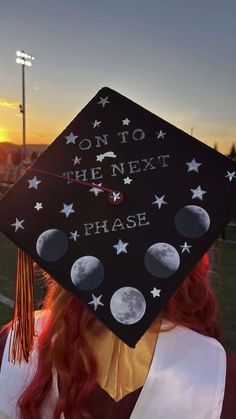 a woman wearing a graduation cap with the words on to the next phase painted on it