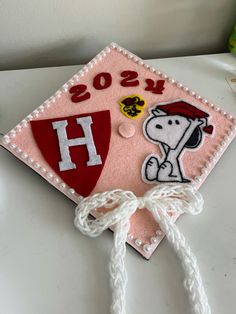 a pink graduation cap with the letter h on it and a snoopy dog embroidered on top