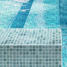 an empty swimming pool with blue tiles on the bottom and water in the back ground