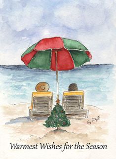 two people sitting under an umbrella on the beach, one is holding a christmas tree