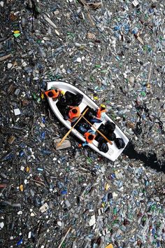 a small boat filled with lots of bottles on top of a beach covered in trash