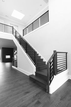 a black and white photo of a staircase in a house with hardwood floors, railings and handrails