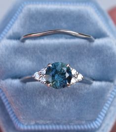 a blue diamond ring sitting on top of a velvet box