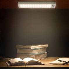 an open book sitting on top of a wooden table next to a lit up light