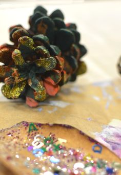 a pine cone sitting on top of a piece of paper next to some glitters