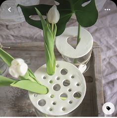 two vases with flowers in them sitting on a wooden tray next to each other