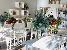 a room filled with lots of white chairs and tables covered in vases full of flowers