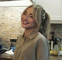 a woman standing in a kitchen smiling at the camera