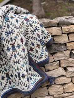 a crocheted blanket sitting on top of a stone wall