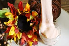 a crochet hook and yarn on a plate with autumn flowers in the background