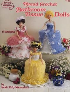 two crocheted dolls in dresses and flowers sitting on top of a book with the title threaded crochet bathroom tissue dolls