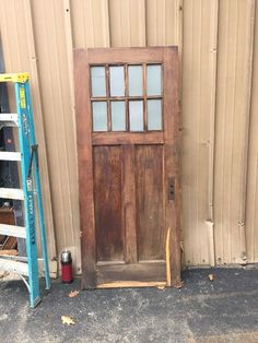 an old wooden door sitting in front of a building next to a blue tool holder