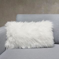 a white furry pillow sitting on top of a couch