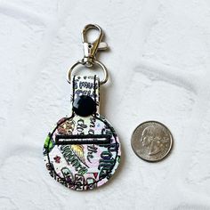 a coin sitting next to a keychain on top of a white cloth covered surface