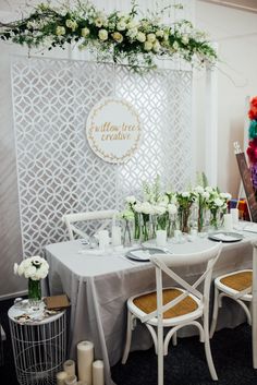 the table is set with white flowers and greenery