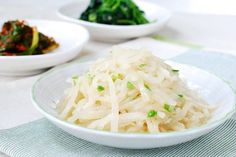 a white plate topped with noodles and broccoli next to other plates of food