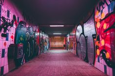 an empty hallway with graffiti all over the walls and tile flooring on both sides