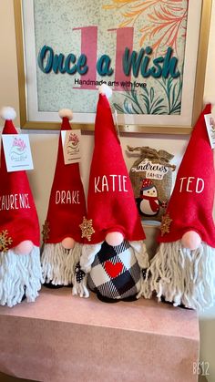 three red and white christmas gnomes with tags on their heads sitting on a shelf