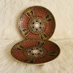 two decorative plates sitting on top of a white rug