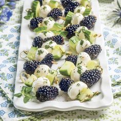 there is a white plate with blackberries and cucumbers on it