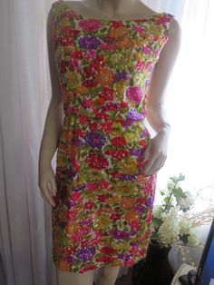 "1950's pencil fit, sleeveless, pointy bust, tapered waist, back metal zipper, floral sequin cocktail dress. The cotton-like floral fabric colors are bright pinks, yellow, cream, orange, red, purple/lilac, greens. The sequins covering the flowers are pinks, yellow, lilac, red, stitched into the flowers. Dress does not have label maker name or size tag, and is great \"Rocker\" condition, for a small figure. Bust (pointy) about 38\", Armholes 16\", Waist 26\", Hip about 38\", Length 33\", Shoulder Yellow Lilac, Flowers Dress, Label Maker, Sequin Cocktail Dress, 80s Dress, Yellow Cream, Purple Lilac, Metal Zipper, Floral Fabric