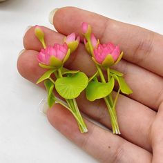 three small pink flowers with green leaves in their hands