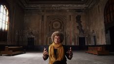 a woman is standing in an old building with her hands up and looking at the camera