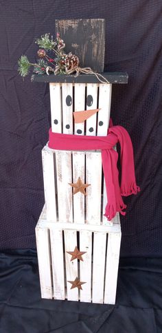 a snowman made out of wooden pallets with red scarf and star decorations on top