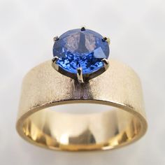 a yellow gold ring with a blue stone