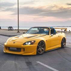 the yellow sports car is parked on the side of the road next to the ocean