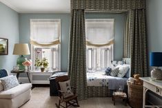 a living room filled with furniture and windows covered in drapes next to a bed