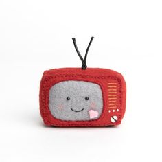 a small red and gray television ornament with a smiling face on it's side