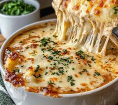 a close up of a bowl of lasagna being lifted with a spatula