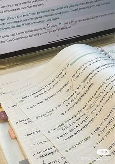 an open book sitting on top of a desk next to a computer monitor