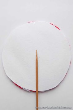 a round piece of white paper with a wooden stick sticking out of it next to the circle