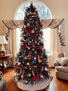 a decorated christmas tree in the corner of a living room with a large round window