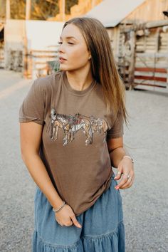 Saddle up with our Horsin' Around Tee. This vintage western t-shirt features a playful horses graphic in classic brown. With short sleeves and a classic fit, it's perfect for any rodeo or just horsin' around. Haylee is wearing size small paired with The Lodonna Skirt Fall Ranch Crew Neck T-shirt, Western-style T-shirt For Western-themed Fall Events, Country Style Short Sleeve T-shirt For Rodeo, Western Style T-shirt For Fall Western-themed Events, Graphic Tee For Western-themed Fall Events, Country Style Short Sleeve Tops For Western-themed Events, Country Style T-shirt For Rodeo In Fall, Western Crew Neck Tops For Rodeo, Country Style Crew Neck Top For Rodeo