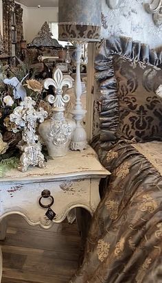 a white table topped with lots of vases and flowers next to a bed covered in curtains