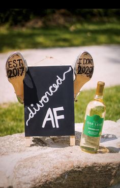 a bottle of alcohol sitting on top of a rock next to a sign with the word wine written on it