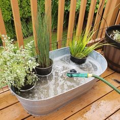 a tub filled with water and plants on top of a wooden deck