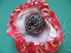 a close up of a flower made out of fabric and brooches on a table