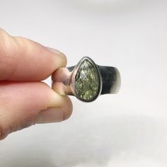 This genuine moldavite ring weighs 6.7 grams and is a size US 8. This rare stone sits in all sterling silver, the front is faceted and the back is raw. Our Moldavite is guaranteed 100% genuine from the Czech Republic. Moldavite comes from a meteor collision with Earth almost 15 million years ago. Found only in the Czech Republic these green Gems are one of the most rare minerals on Earth. This tektite is composed of natural glass and is created when a meteorite collides with earth resulting in t Moldavite Mens Ring, Moldavite Aesthetic, Moldavite Meaning, Moldavite Earrings, Moldavite Jewelry, Rare Stone, Green Gems, Natural Texture, Druzy Ring