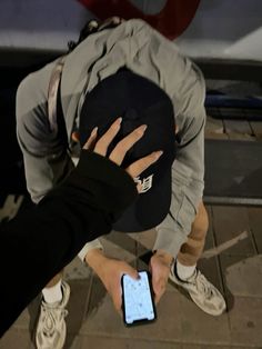 a person holding a cell phone in their hand while standing on the ground next to a car