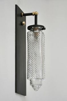 a glass light hanging from the side of a wall