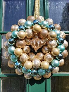 a christmas wreath is hanging on the front door with gold and blue ornaments around it