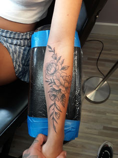 a woman with a flower tattoo on her arm sitting in front of a hair dryer