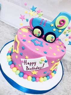 a pink birthday cake decorated with stars and a blue cat on top that says happy birthday