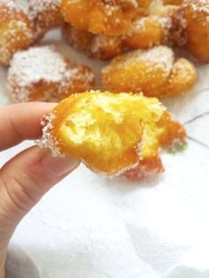 a person holding up a powdered sugar covered doughnut